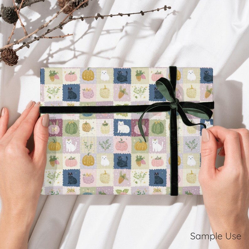 May include: A rectangular gift wrapped in patterned paper featuring a grid of illustrations including black and white cats, pumpkins in shades of yellow, green, and pink, and sprigs of greenery, tied with a dark green velvet ribbon.