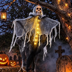 May include: A hanging skeleton decoration featuring a skull head draped in tattered, layered grey and black fabric. The figure is illuminated by a vertical string of warm yellow LED lights running down the center, creating a glowing effect.
