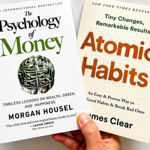 May include: Two books are displayed, one titled "The Psychology of Money" with a brain graphic, and the other "Atomic Habits." The first book is by Morgan Housel, and the second is by James Clear. Both are bestsellers.