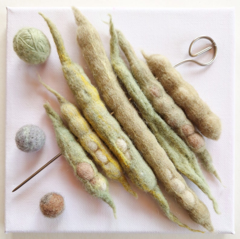 bean pods handmade of felted wool on a skewer sewn to the canvas with the subframe
