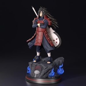 Puede incluir: Figura detallada de un personaje con un atuendo azul oscuro y rojo, con pelo largo negro y una espada. La figura se encuentra sobre una base rocosa con detalles de llamas azules y un emblema circular.