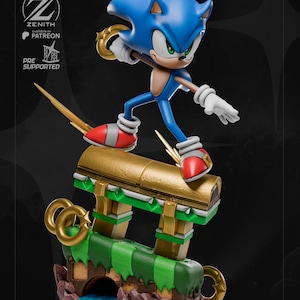 May include: A blue Sonic the Hedgehog figurine in a dynamic pose, holding a golden ring. The figure stands on a detailed platform with a gold, green, and brown design. The base includes a tunnel and water feature. The Zenith logo and "Pre Supported" text are visible.