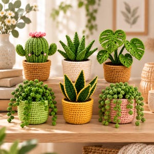 Puede incluir: Seis plantas en maceta tejidas a ganchillo dispuestas en dos filas. La fila superior presenta un cactus sonriente con flores rosas, una suculenta verde y una planta monstera. La fila inferior incluye una planta colgante, una sansevieria y otra planta colgante.