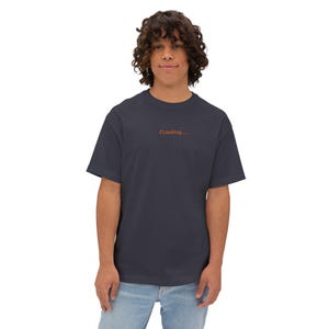 May include: A navy blue t-shirt with the word "Clauding..." printed in orange. The shirt is a solid color and has short sleeves. The person wearing the shirt is smiling.