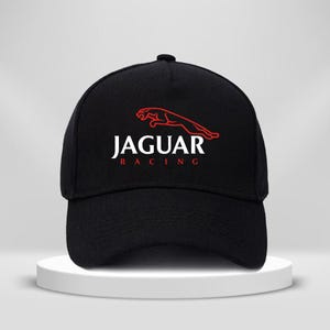May include: Black baseball cap featuring the Jaguar Racing logo in white and red. The cap has a curved brim and a structured crown. The Jaguar logo is a red leaping jaguar. The text "JAGUAR" is above "RACING" in white.