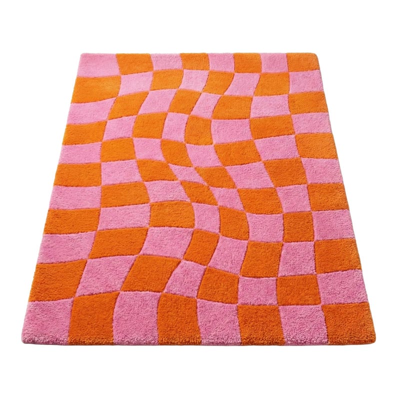 May include: A rectangular area rug featuring a vibrant checkerboard pattern in bright orange and pink. The grid design is distorted with a wavy, warped effect that creates a sense of movement across the entire surface of the tufted textile floor covering.