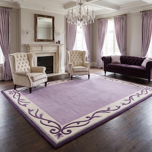 May include: A rectangular area rug featuring a solid lavender centre panel surrounded by a cream-coloured border. The border is decorated with a dark purple scrolling vine and leaf pattern that extends along all four sides of the rug.
