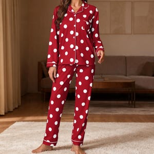 Può includere: Pigiama rosso a pois bianchi. La parte superiore a maniche lunghe ha una chiusura con bottoni e finiture bianche. I pantaloni abbinati hanno un design a gamba dritta. Il pigiama è realizzato in un materiale morbido e confortevole.