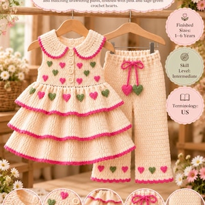 May include: A cream-colored crochet dress and pants set featuring a Peter Pan collar, three scalloped ruffle tiers, and pink and sage-green heart appliqués. The pants include a drawstring waist with matching heart accents.