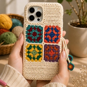 Puede incluir: Una funda de teléfono de ganchillo color crema con cuatro motivos cuadrados de la abuela en tonos azul verdoso, burdeos, azul, naranja, amarillo, verde y morado. Incluye una correa de muñeca a juego con dos pequeños adornos florales.