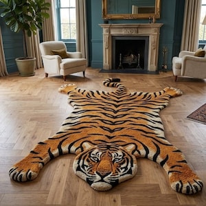 Op de afbeelding: Een oranje en zwart tapijt in de vorm van een tijger, met een gedetailleerd gezicht en poten. Het tapijt is gemaakt van een zacht materiaal en ligt op een houten vloer. Het ontwerp van het tapijt bootst het vachtpatroon van een tijger na.