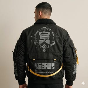 May include: Black bomber jacket with a black faux fur collar and multiple pockets. The jacket features a large gray graphic on the back with the text "CROSS BONE" and other Japanese characters. A yellow strap detail adds a pop of color.