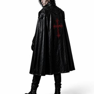 May include: A black, faux leather cape with a red cross design on the back. The cape is worn with black boots and gloves. The person is looking over their shoulder. The cape has a textured appearance.