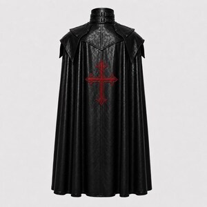 May include: Black faux leather cape with a red cross emblem on the back. The cape features a high collar with buckle details and a flowing design. The garment has a textured appearance and a gothic aesthetic.