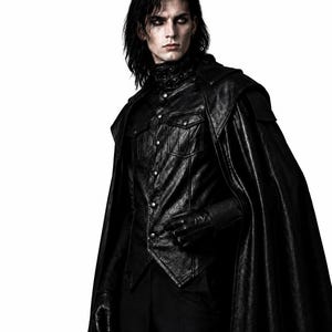 May include: A person wearing a black leather jacket with a high collar and a matching cape. The jacket has silver buttons and a textured appearance. The person is also wearing black gloves and pants. The background is white.