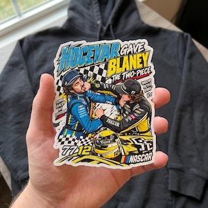 May include: A rectangular sticker featuring a cartoon illustration of two race car drivers in blue and yellow racing suits fighting. The text reads Hocevar Gave Blaney The Two-Piece, Some Races Hit Different, NASCAR After Dark, 77, 12, and NASCAR.