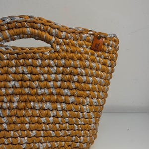 Minibolso color camel con inserciones doradas y base de piel sintética.