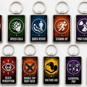 May include: A set of eleven rectangular metal keychains featuring colorful graphic icons and text labels including Jugger-Nog, Speed Cola, Quick Revive, Stamin-Up, PHD Flopper, Deadshot Daiquiri, Death Perception, Double Tap Root Beer, Vulture Aid, Elemental Pop, and Melee Macchiato.