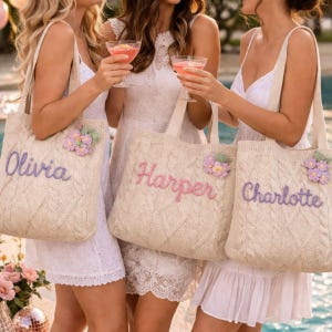 May include: Three beige cable-knit tote bags featuring embroidered names in cursive script. Each bag is personalized with the names Olivia, Harper, or Charlotte and decorated with a small cluster of crocheted purple and yellow flowers.