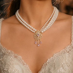 Peut inclure: Un collier de perles à plusieurs rangs avec un pendentif en filigrane doré centré sur une pierre précieuse violet clair. Le pendentif comprend trois pierres violet clair en forme de goutte et de petits cristaux clairs sur une monture.