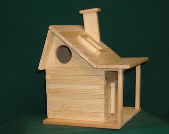 May include: A wooden birdhouse with a small porch and a chimney. The birdhouse is made of natural wood and has a round opening for birds to enter.