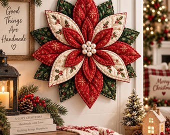 Puede incluir: Un adorno de pared de tela acolchada con forma de flor de pascua, con pétalos superpuestos en rojo, crema y verde oscuro con patrones de copos de nieve dorados y bayas de acebo. El centro está decorado con seis perlas blancas y un cordel.