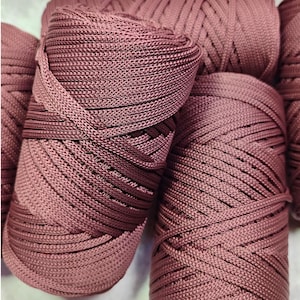 May include: Multiple spools of dusty rose colored cord arranged in a cluster. Each spool features a tightly wound, smooth, braided synthetic material with a consistent texture and a subtle sheen, creating a uniform appearance across all pieces.