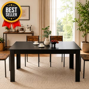 May include: A rectangular black dining table with four matching chairs featuring dark wood-grain seats and backrests. The table surface holds two white cups on saucers, a white ribbed vase with green foliage, and a small black bowl filled with red berries.