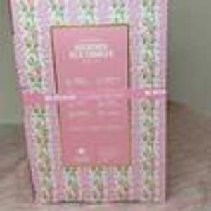 Puede incluir: Una caja de regalo con un estampado floral rosa y blanco, atada con una cinta rosa. La caja tiene una etiqueta rectangular rosa con texto. El fondo es un estampado floral rosa.