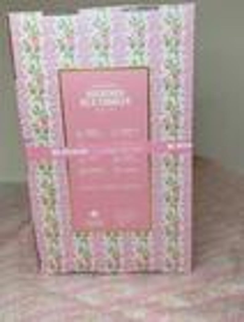 Puede incluir: Una caja de regalo con un estampado floral rosa y blanco, atada con una cinta rosa. La caja tiene una etiqueta rectangular rosa con texto. El fondo es un estampado floral rosa.