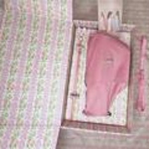 Puede incluir: Un juego de cesta de picnic con un estampado floral rosa y blanco. El juego incluye una manta rosa, una camisa rosa, un tenedor, un cuchillo y una cuchara. La cesta est&aacute; abierta, revelando el contenido. La manta est&aacute; doblada en el lado izquierdo.