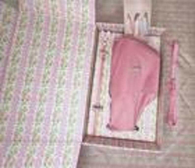 Puede incluir: Un juego de cesta de picnic con un estampado floral rosa y blanco. El juego incluye una manta rosa, una camisa rosa, un tenedor, un cuchillo y una cuchara. La cesta est&aacute; abierta, revelando el contenido. La manta est&aacute; doblada en el lado izquierdo.