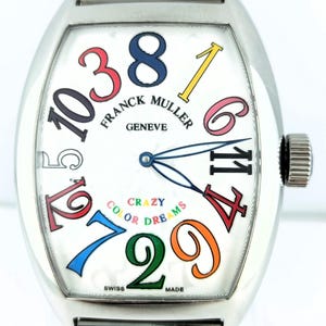 Puede incluir: Un reloj Franck Muller de acero inoxidable con esfera blanca y números coloridos. La esfera del reloj presenta las palabras "CRAZY COLOR DREAMS" y "FRANCK MULLER GENEVE". El reloj tiene una correa plateada.