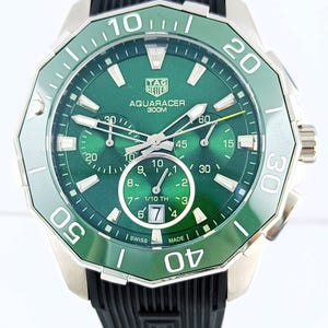 Könnte beinhalten: Eine silberne und grüne Tag Heuer Aquaracer 300M Uhr mit einem schwarzen Kautschukarmband. Das Zifferblatt der Uhr ist grün mit weißen Ziffern und Zeigern. Die Uhr hat mehrere Hilfszifferblätter.