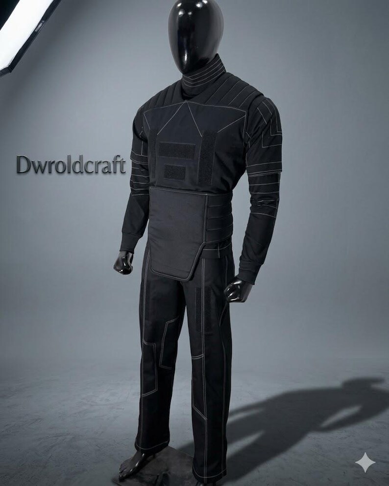 May include: Black tactical suit with white stitching, displayed on a mannequin. The suit includes a long-sleeved top, pants, and a waist protector. The top has a high collar and geometric design. The pants have reinforced knee and thigh panels. The text "Dwroldcraft" is visible.