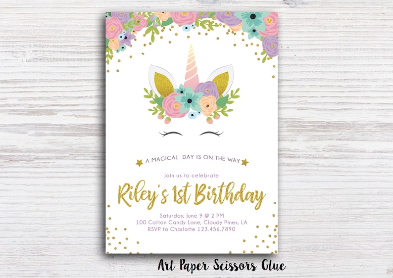 May include: A white invitation card with a unicorn design. The unicorn has a pink horn, gold ears, and is surrounded by floral elements. The text reads "A Magical Day Is On The Way" and "Riley's 1st Birthday".