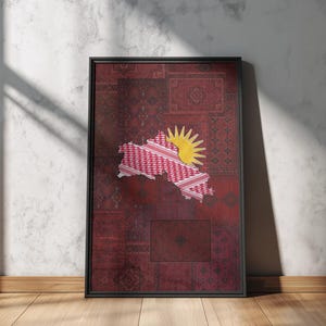 May include: Framed artwork showing a map outline with a red and white pattern, set against a patchwork of burgundy and red patterned fabric. A yellow sunburst design is in the upper right corner. The artwork is in a black frame.