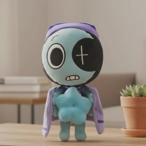 May include: A plush doll with a light blue face, a black eye patch, and a purple nightcap and cape. The doll is holding a light blue star and has a stitched mouth. The doll is standing on a wooden surface.