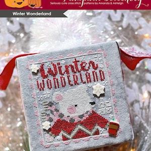 May include: Cross stitch pattern for a winter wonderland scene featuring a cute animal wearing a red and white sweater and holding a cup of coffee. The pattern is titled "Winter Wonderland" and is from The Frosted Pumpkin Stitchery.