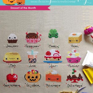 Può includere: Un grafico di punto croce per un calendario mensile di dessert. Ogni mese presenta un dolce carino in stile cartone animato, come un cupcake, un cono gelato e una torta di zucca. Il grafico è intitolato "The Frosted Pumpkin Stitchery" e "Dessert of the Month".