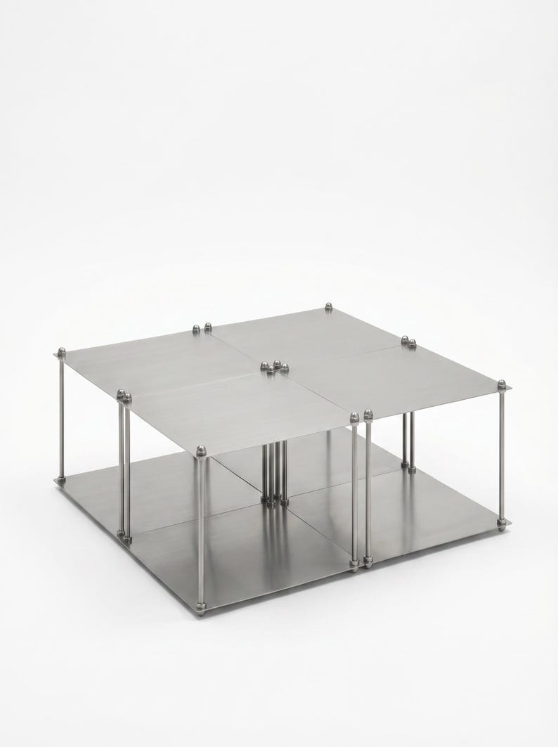 May include: A modern, two-tiered metal display stand with a square base and top. The stand is constructed with four square panels and supported by vertical metal rods and bolts. The overall design is minimalist and industrial.