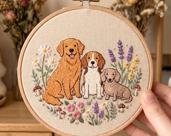 Puede incluir: Arte de aro bordado con tres perros: un golden retriever, un beagle y un dachshund. Los perros están rodeados de flores bordadas, incluyendo margaritas, lavanda y rosas, con acentos de setas. El aro es de madera.