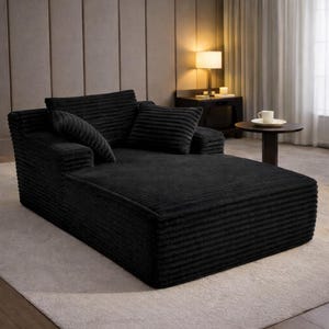 Black corduroy chaise lounge sofa with plush padding and low profile, ideal for modern or minimalist interiors.
