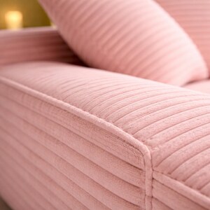 Close-up of pink corduroy chaise lounge seat and cushions, showing ribbed texture, soft fabric, and plush padding.