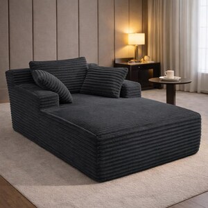 Dark gray corduroy chaise lounge with oversized cushions and minimalist design, styled in a contemporary room.
