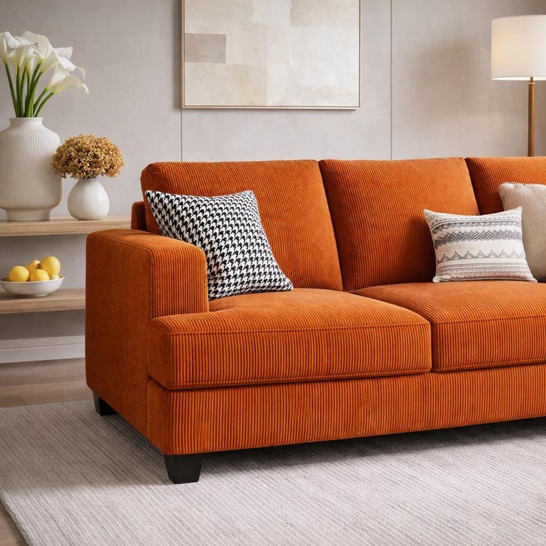 Orange corduroy sofa close up, textured upholstery with accent pillows, modern 3 seater couch styling, cozy home decor
