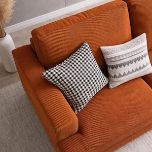 Top angle orange corduroy sofa, plush seat cushions and wide armrests, modern upholstered couch detail