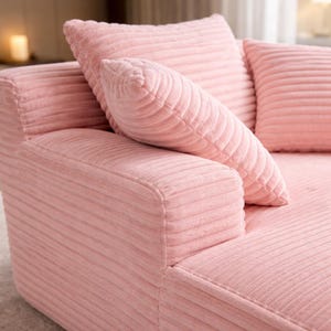 Close-up of pink corduroy chaise lounge armrest and cushions, highlighting ribbed texture and soft upholstery.