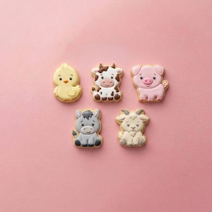 May include: Five decorated sugar cookies shaped like farm animals, including a yellow chick, a brown and white cow, a pink pig, a gray donkey, and a cream-colored goat, all featuring detailed icing designs with smiling faces and distinct features.