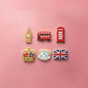 May include: Six decorated cookies featuring London-themed shapes: a tan clock tower, a red double-decker bus, a red telephone box, a gold crown with colorful jewels, a white teacup with blue floral patterns, and a rectangular Union Jack flag.